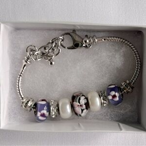 Silver beaded bracelet with purple flowers, pearl and sparkle accents.